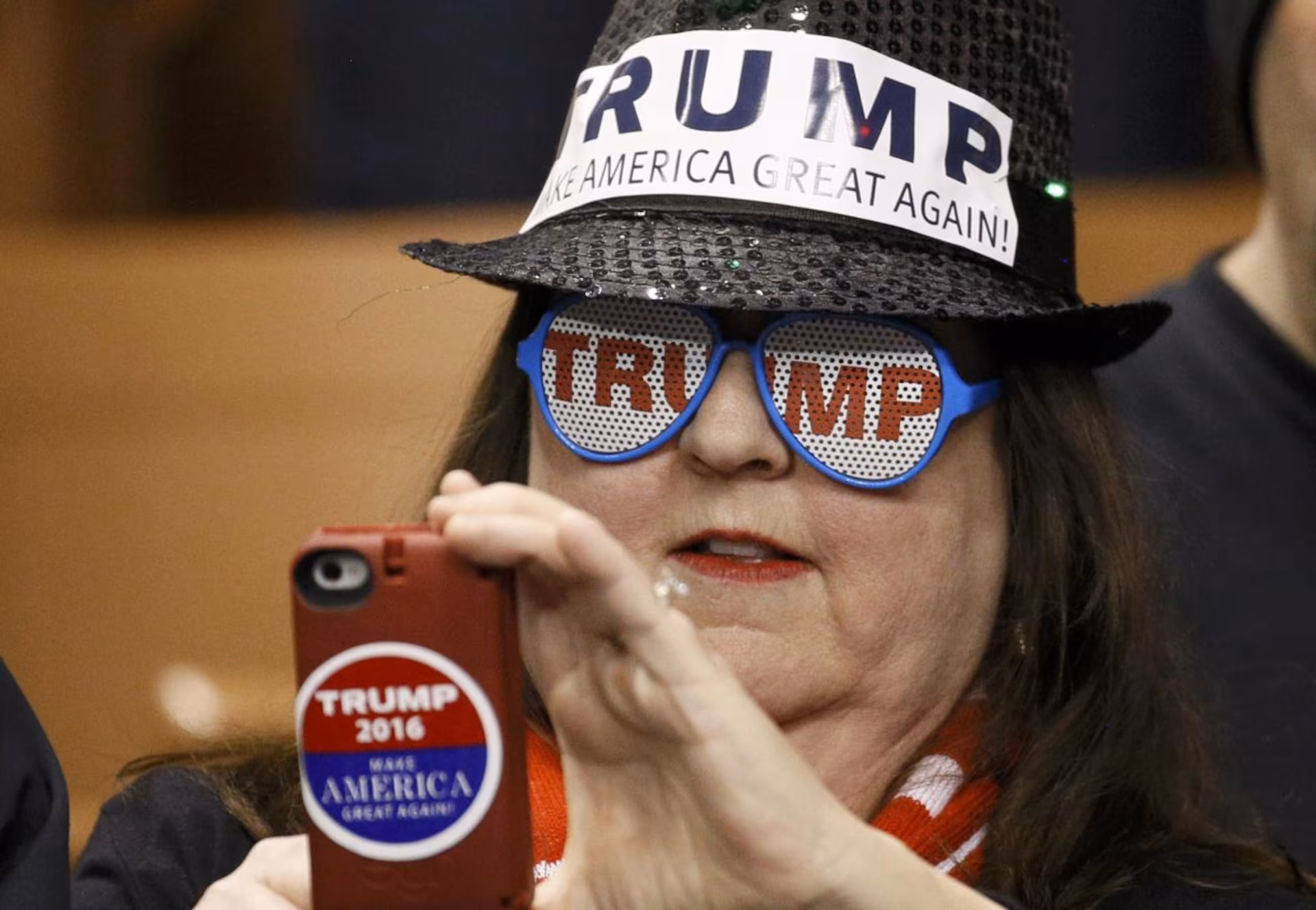 fat woman wearing TRUMP Make America Great Again hat, TRUMP sunglasses and holding phone with a TRUMP decal.